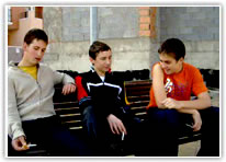 Tres chicos sentados en un banco fumando