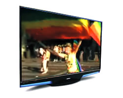Televisor mostrando desfile con chica agitando bandera arco iris 